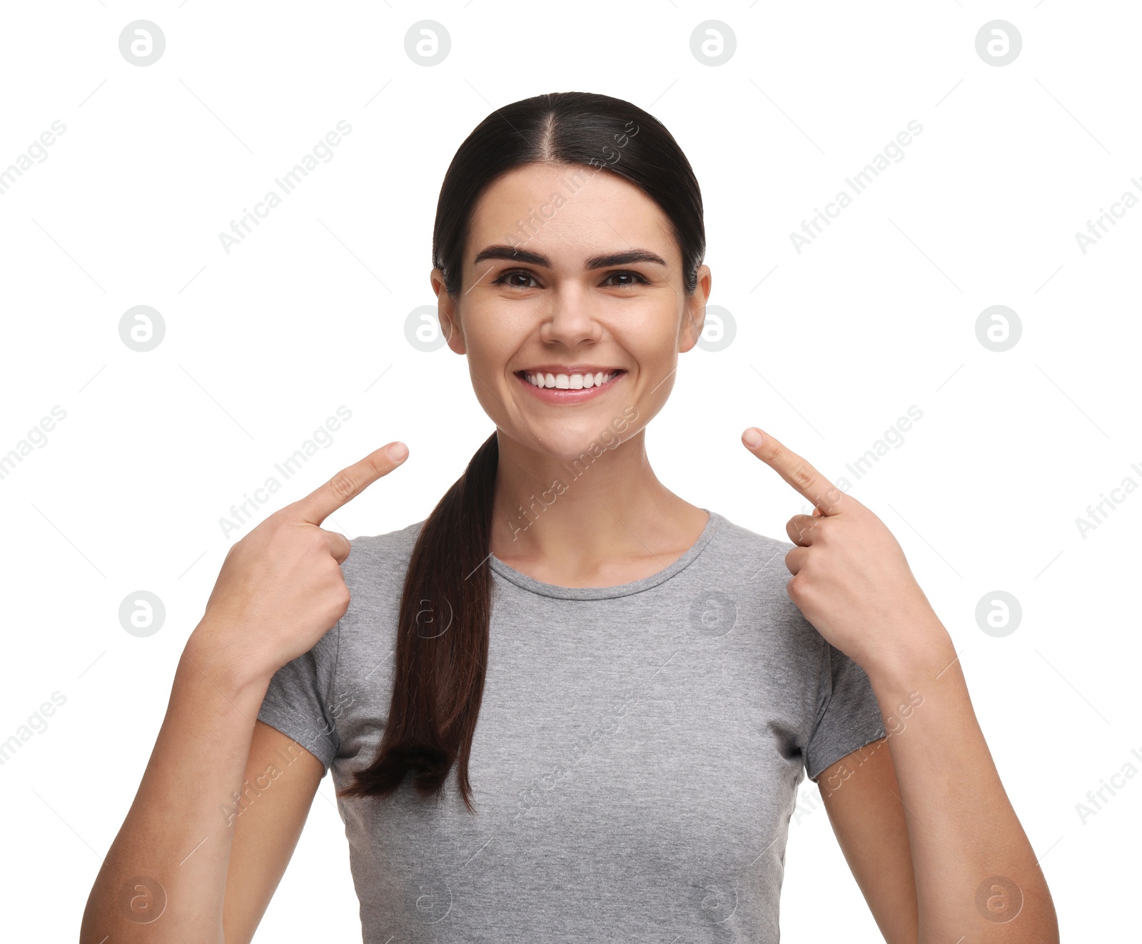 Photo of Young woman pointing at her clean teeth and smiling on white background