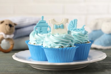 Beautifully decorated baby shower cupcakes for boy with cream and toppers on grey wooden table