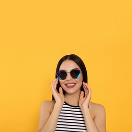 Photo of Attractive happy woman in fashionable sunglasses against orange background