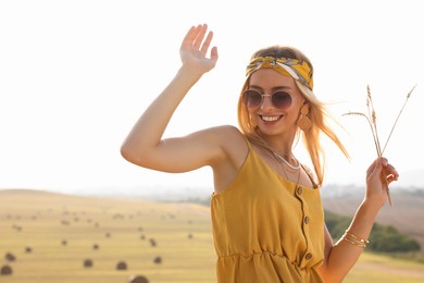 Beautiful happy hippie woman with spikelets in field, space for text