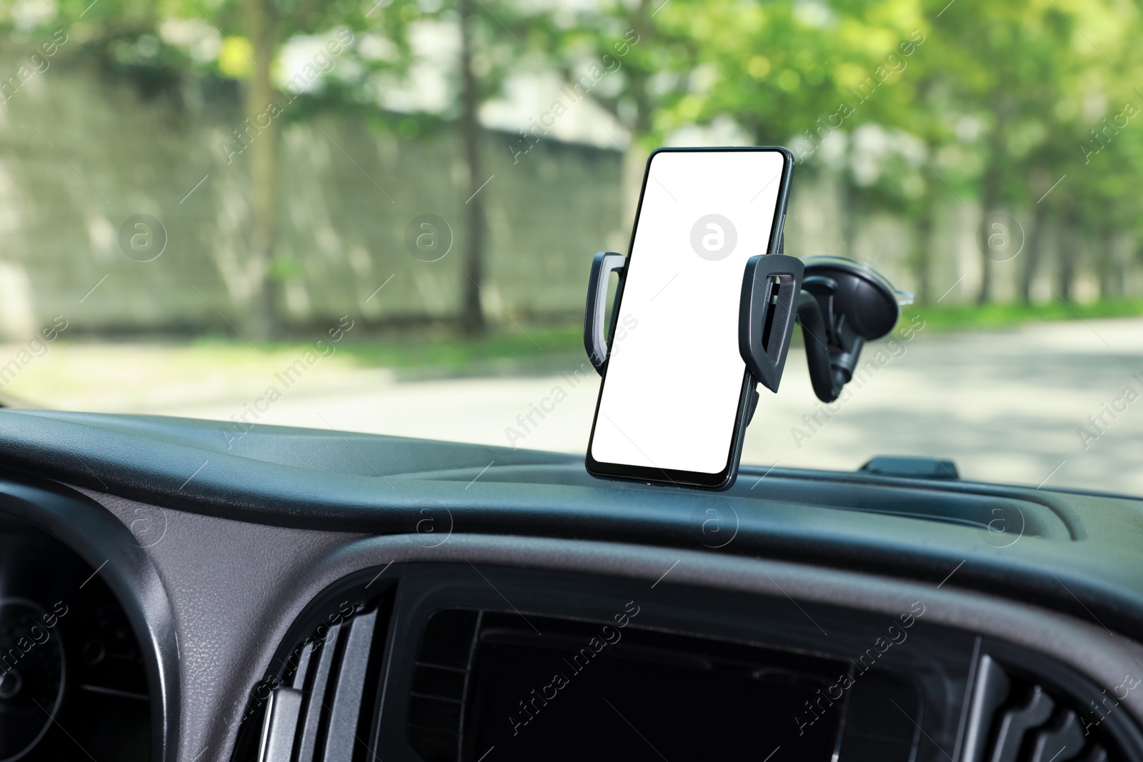 Photo of Car holder with modern mobile phone on windshield of automobile. Mockup for design