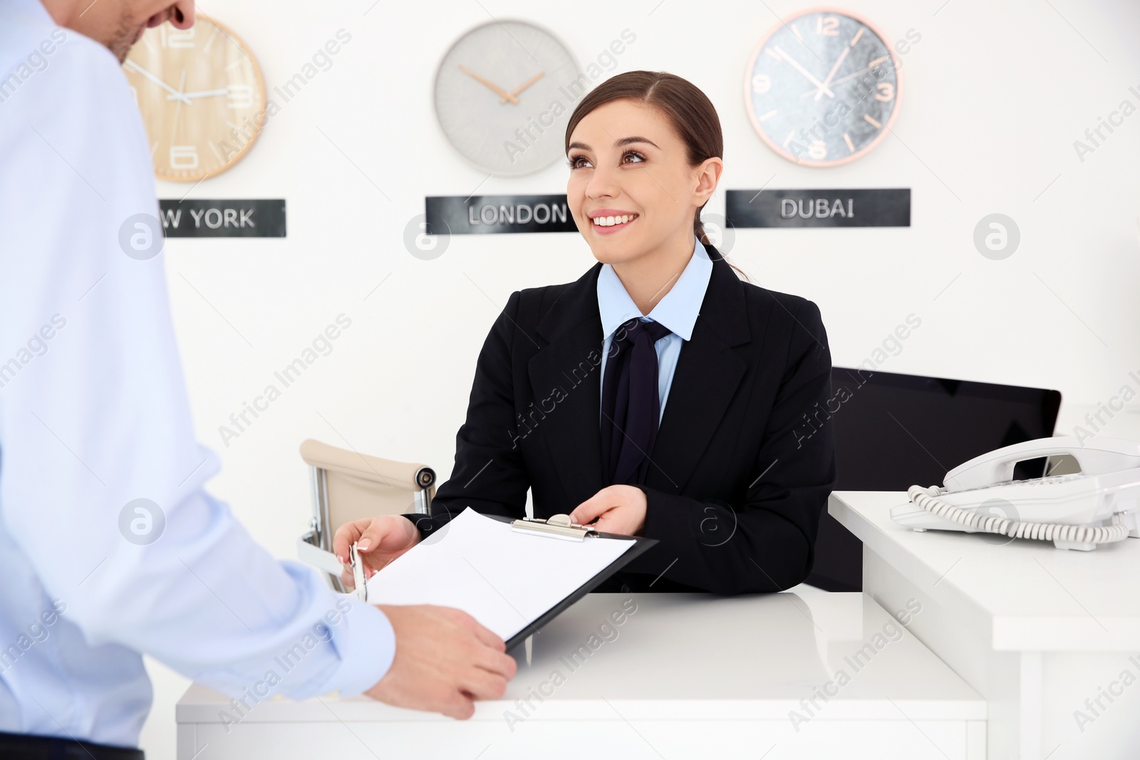 Photo of Young man filling form at reception desk in hotel