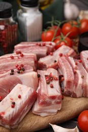 Photo of Cut raw pork ribs with peppercorns on table, closeup