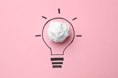 Photo of Idea concept. Light bulb made with crumpled paper and drawing on pink background, top view