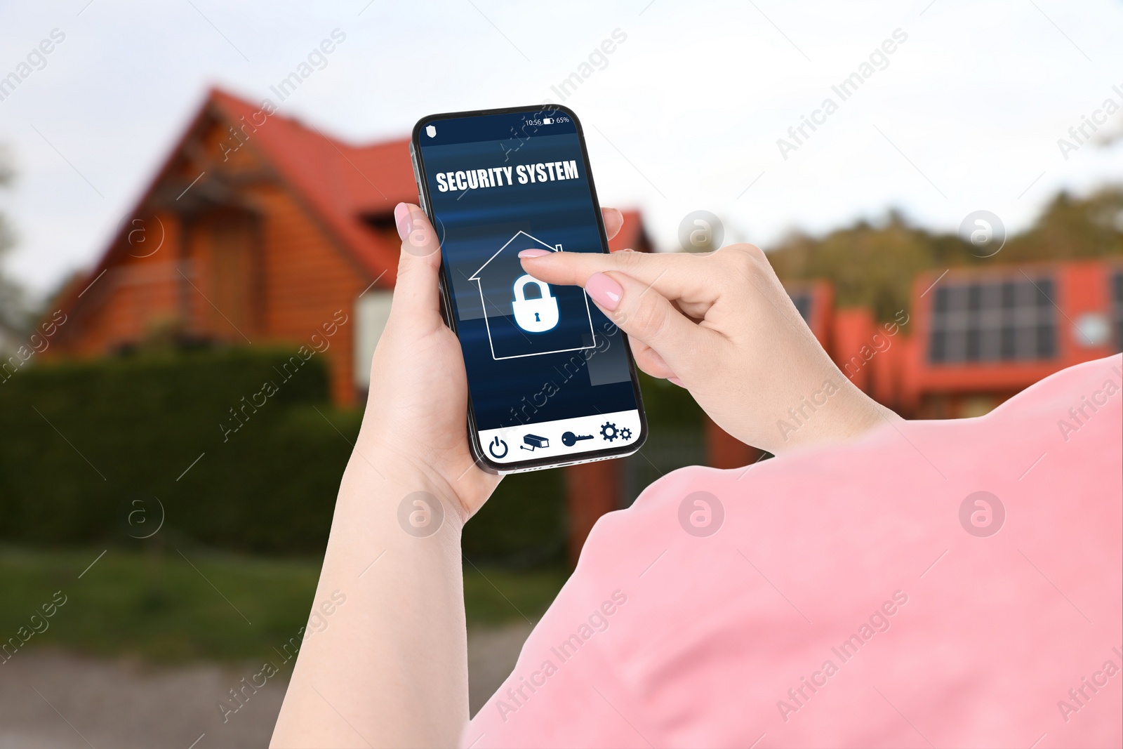 Image of Woman using home security system application on smartphone outdoors, closeup