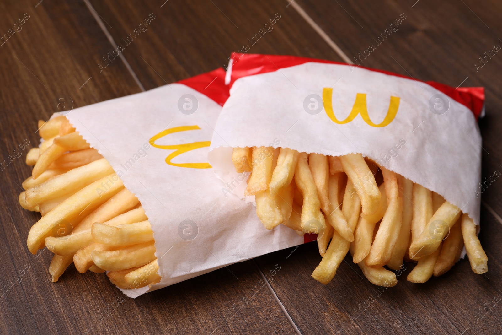 Photo of MYKOLAIV, UKRAINE - AUGUST 12, 2021: Two small portions of McDonald's French fries on wooden table, closeup