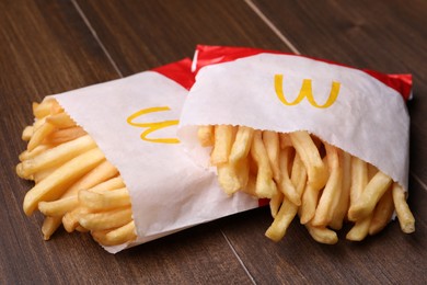 Photo of MYKOLAIV, UKRAINE - AUGUST 12, 2021: Two small portions of McDonald's French fries on wooden table, closeup