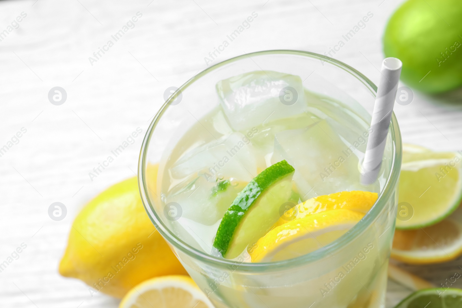 Photo of Glass of natural lemonade with citrus fruits on table, closeup