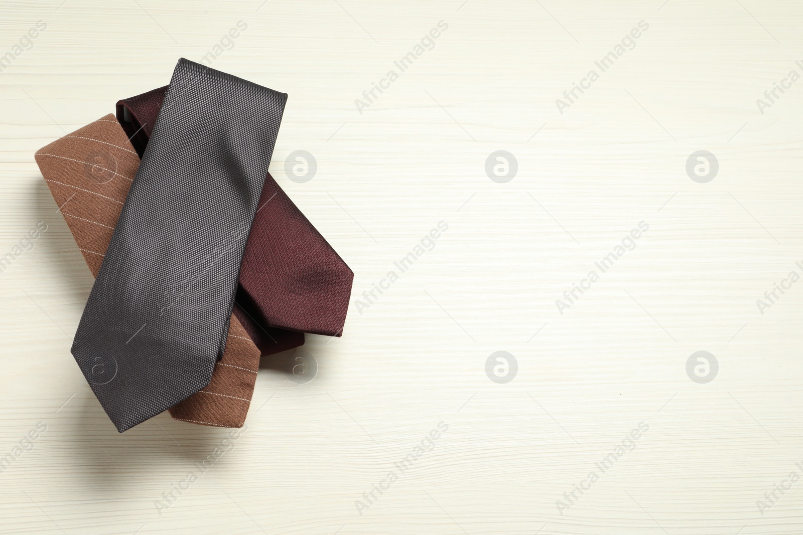 Photo of Different neckties on white wooden table, top view. Space for text