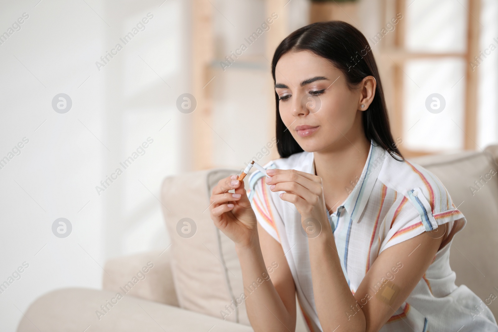 Photo of Young woman with nicotine patch and cigarette at home