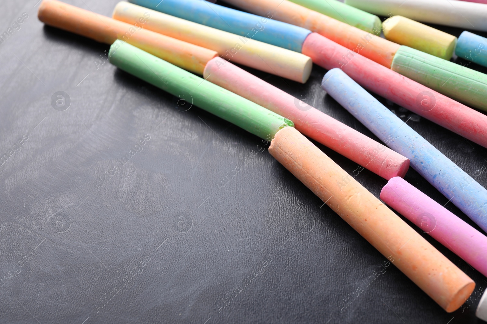 Photo of Pieces of color chalk on blackboard, space for text