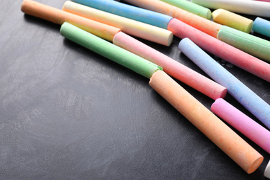 Pieces of color chalk on blackboard, space for text