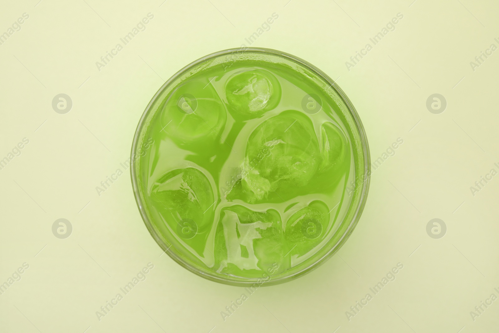 Photo of Glass of delicious iced matcha tea on green background, top view