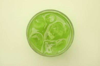 Glass of delicious iced matcha tea on green background, top view