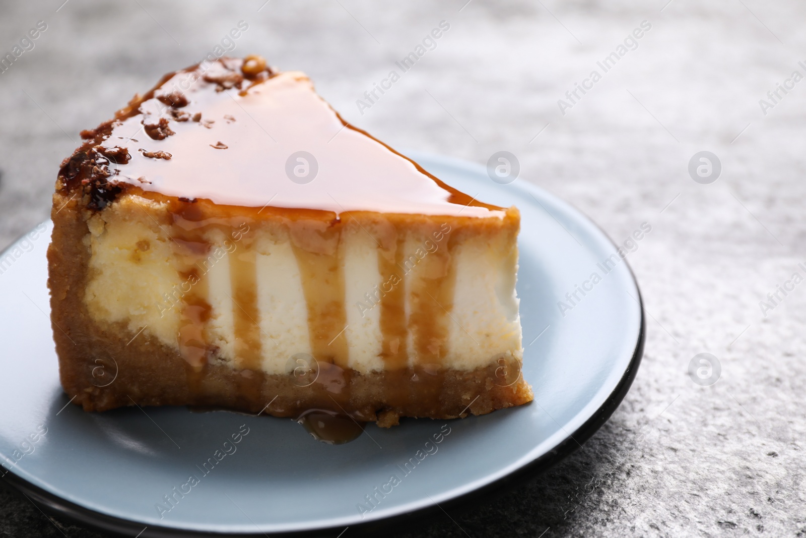 Photo of Piece of delicious cake with caramel served on grey table, closeup