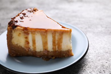 Photo of Piece of delicious cake with caramel served on grey table, closeup