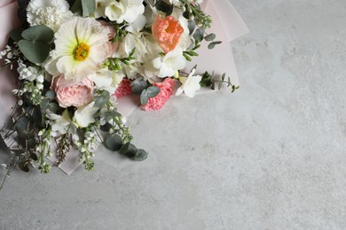 Photo of Bouquet of beautiful flowers on light grey table, above view. Space for text