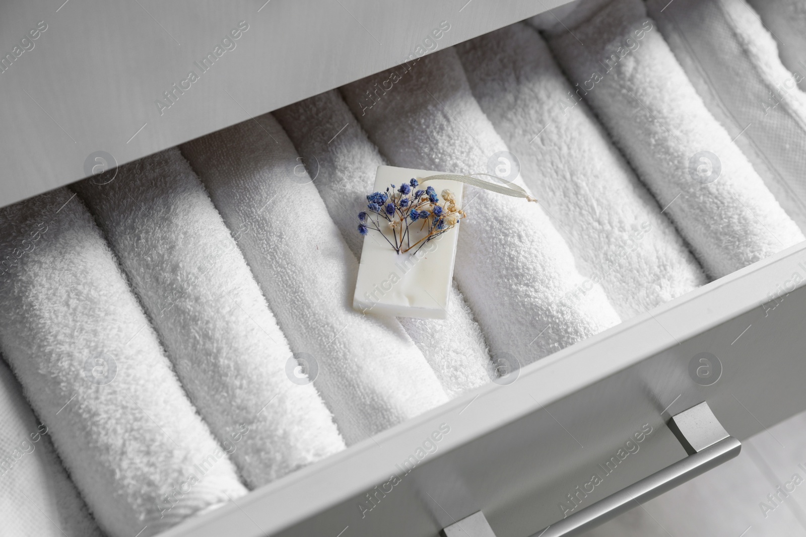 Photo of Beautiful scented wax sachet in dresser drawer with white towels, closeup