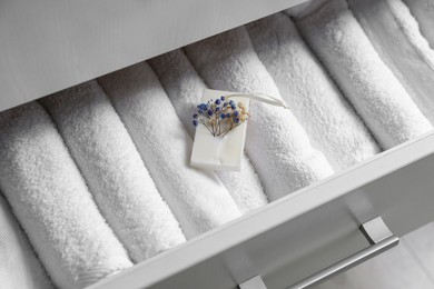 Photo of Beautiful scented wax sachet in dresser drawer with white towels, closeup