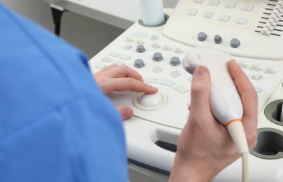 Photo of Sonographer operating modern ultrasound machine in clinic, closeup