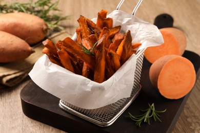 Photo of Frying basket with sweet potato fries on table, closeup