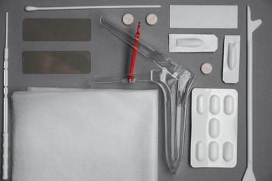 Photo of Sterile gynecological examination kit and medicaments on grey background, flat lay