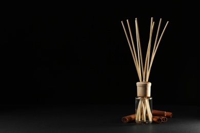 Photo of Reed air freshener with anise and cinnamon on black background, space for text