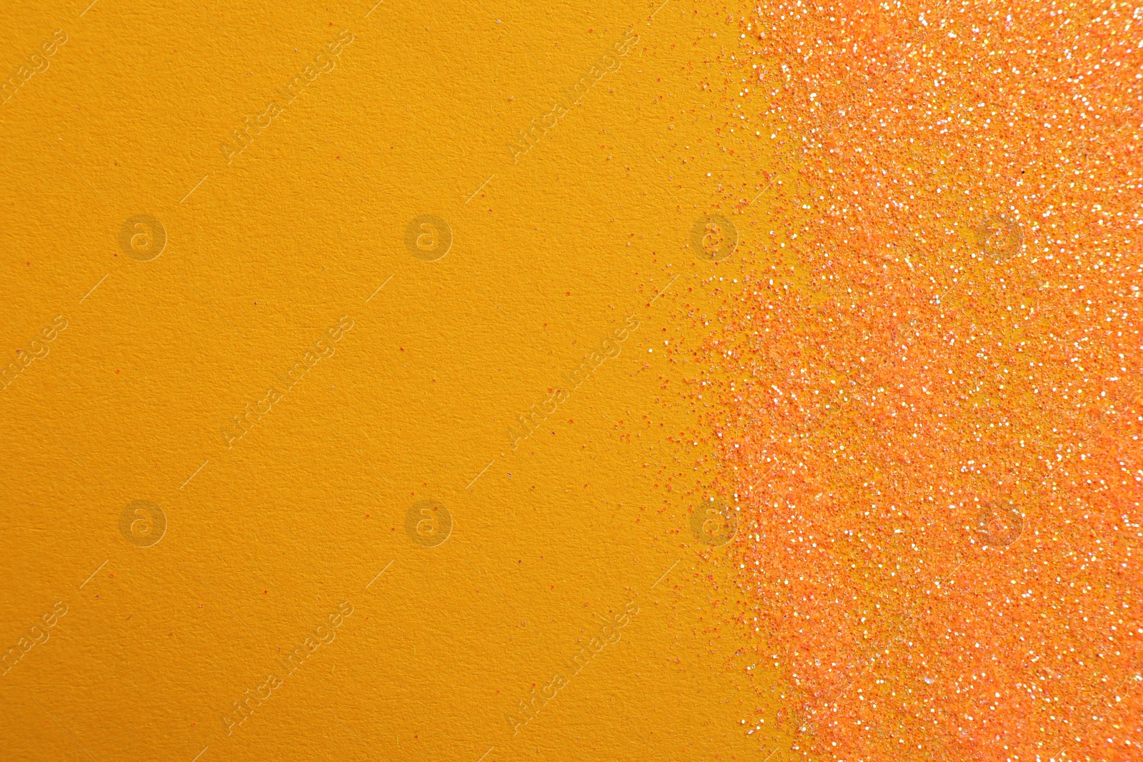 Photo of Shiny bright glitter on orange background, flat lay. Space for text