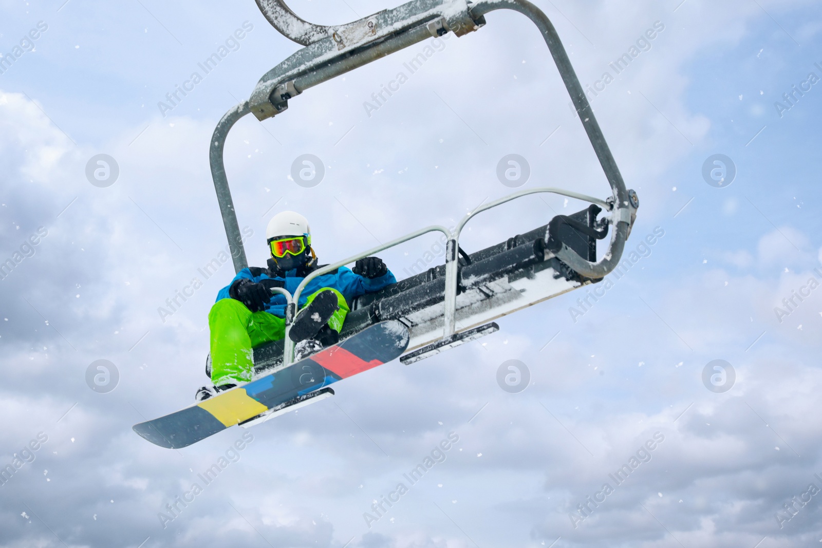 Photo of Snowboarder using ski lift at mountain resort. Winter vacation