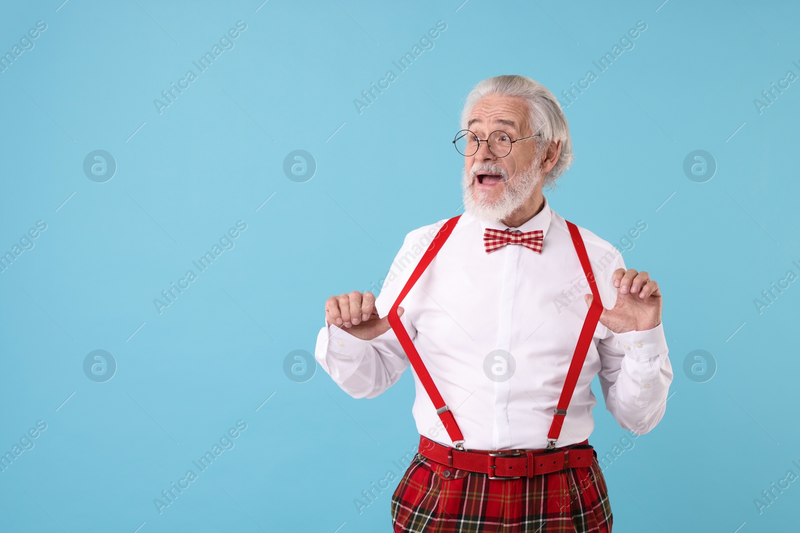 Photo of Portrait of stylish grandpa with glasses and bowtie on light blue background, space for text