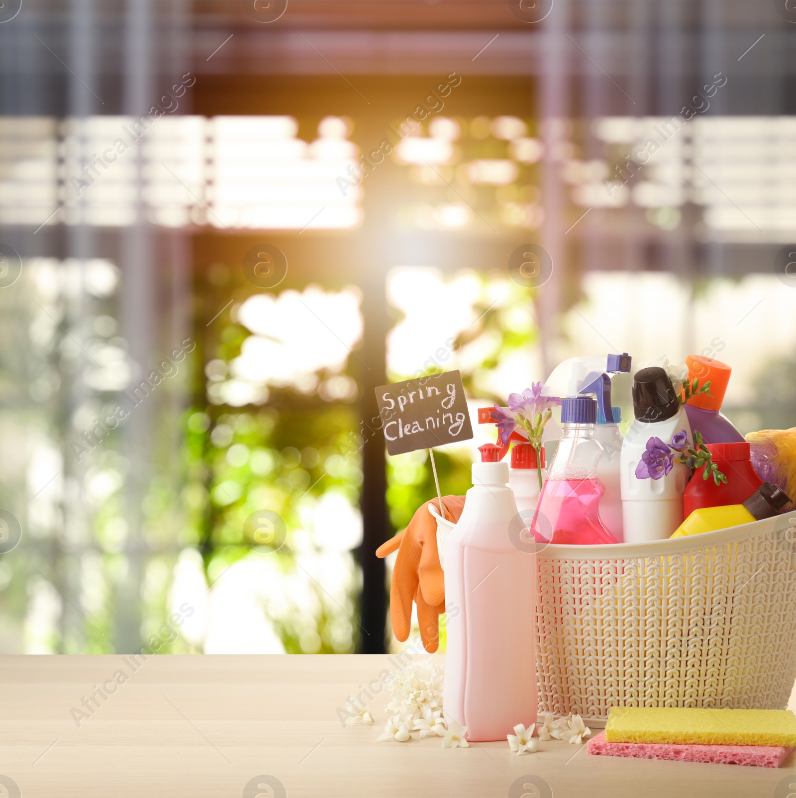 Image of Plastic basket with different detergents on wooden table indoors, space for text. Spring cleaning concept 