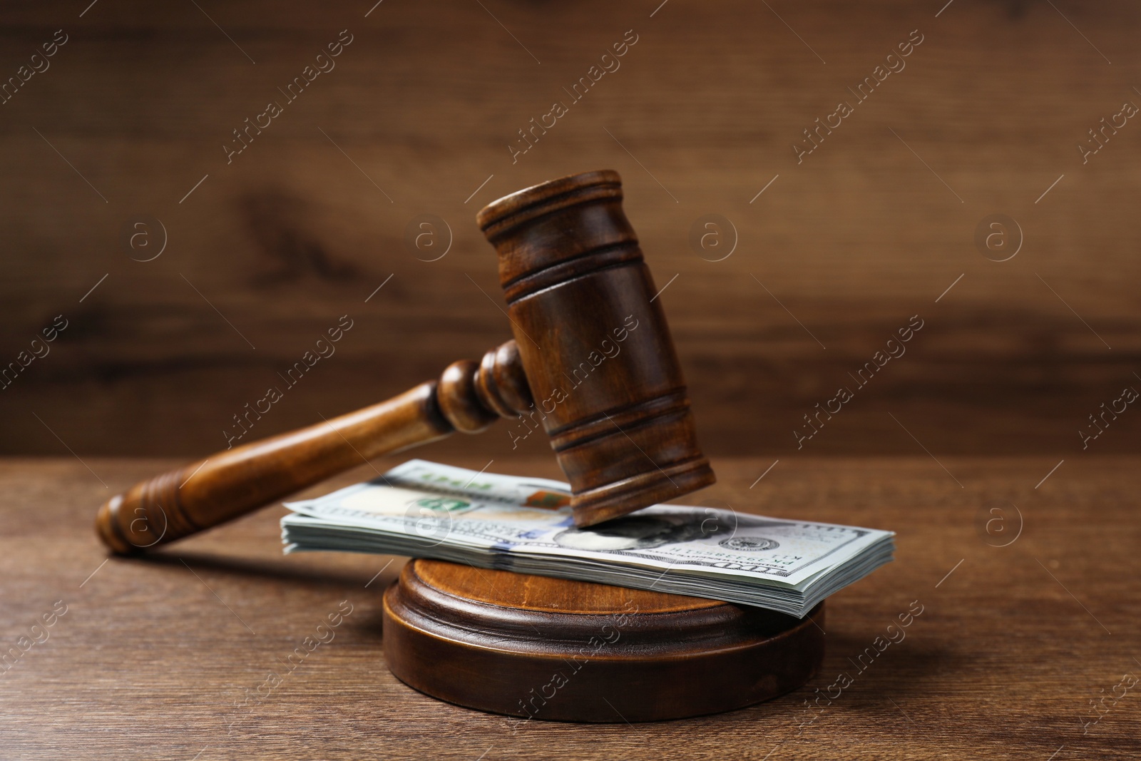 Photo of Law gavel with stack of dollars on wooden table, closeup