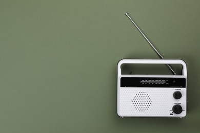 Photo of Retro radio receiver on olive background, top view. Space for text