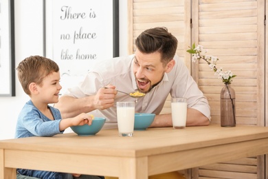 Father and son having breakfast with milk at table