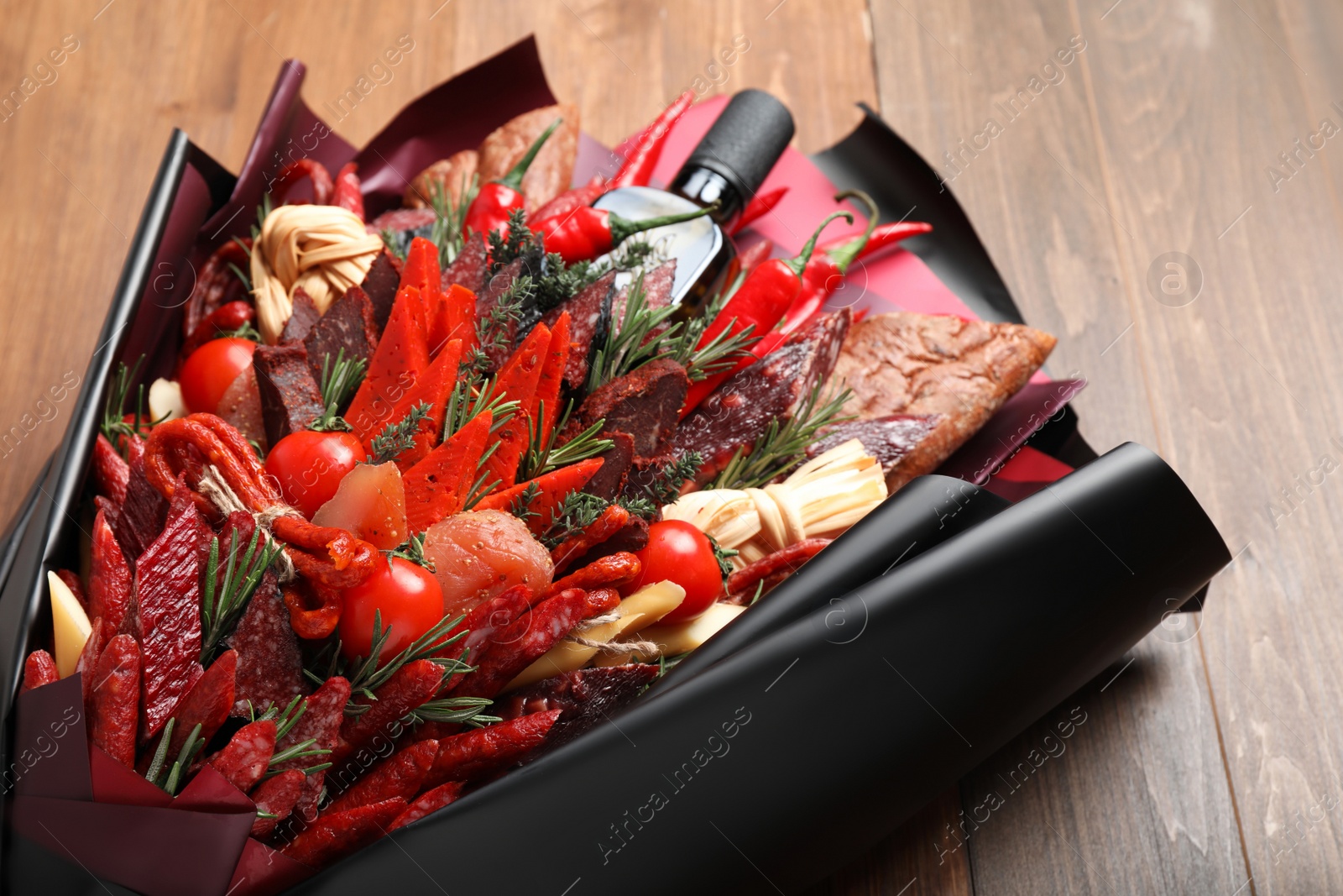 Photo of Beautiful edible bouquet with meat, cheese and vegetables on wooden table, closeup