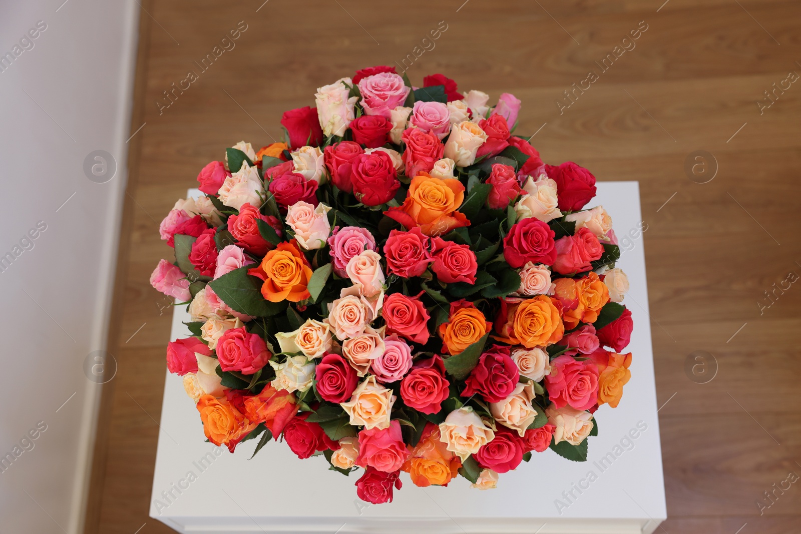 Photo of Bouquet of beautiful roses on white table indoors, top view
