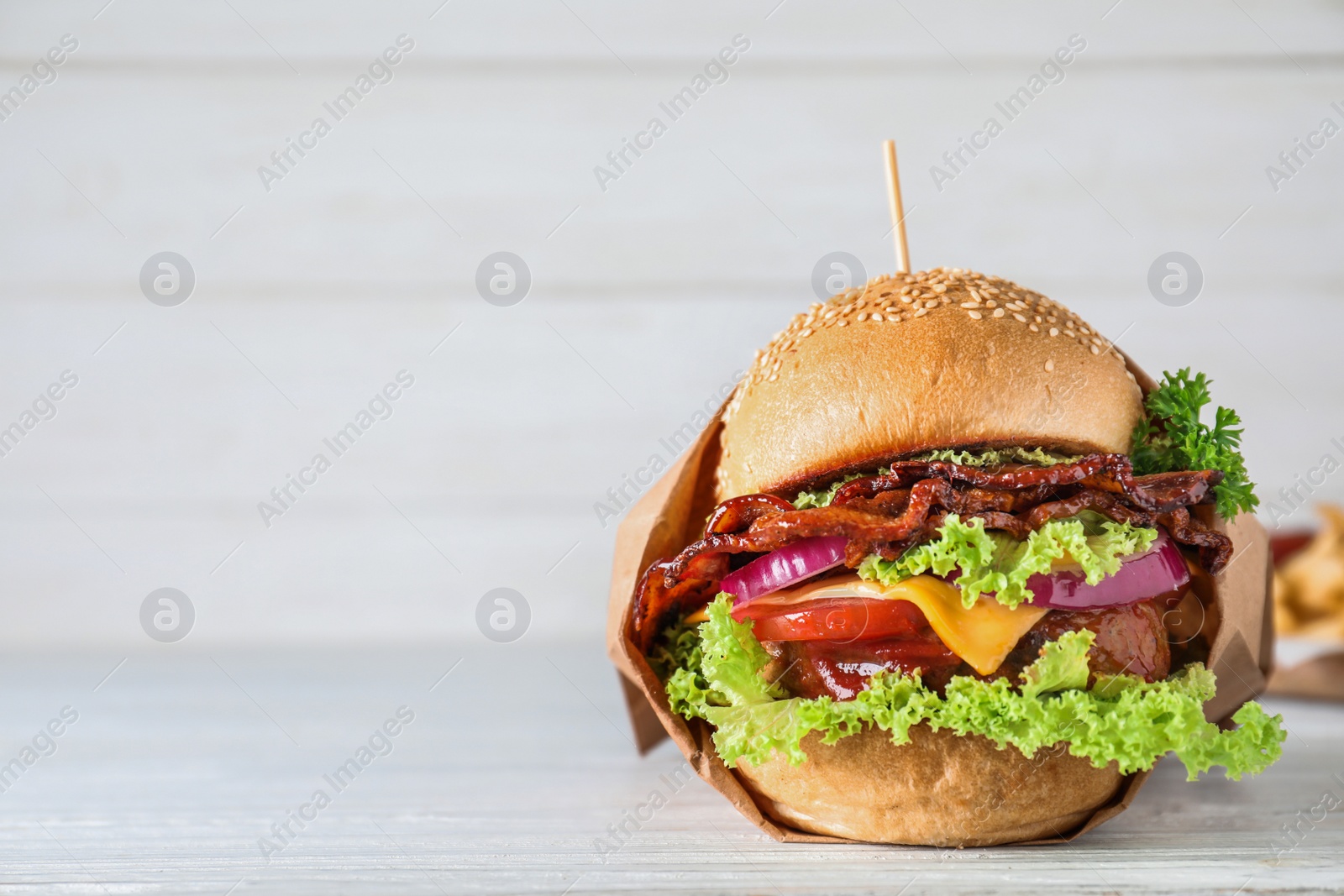 Photo of Fresh juicy bacon burger on white wooden table. Space for text