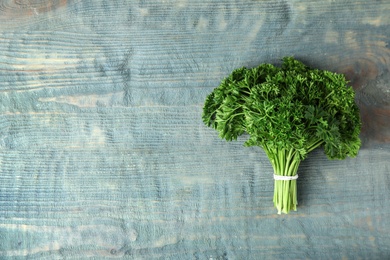 Photo of Bunch of fresh green parsley on blue wooden background, top view. Space for text