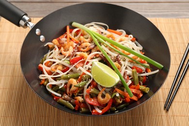 Photo of Shrimp stir fry with noodles and vegetables in wok on table
