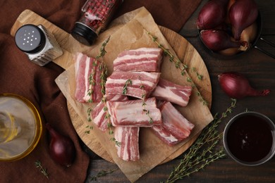 Photo of Flat lay composition with cut raw pork ribs and sauce on wooden table