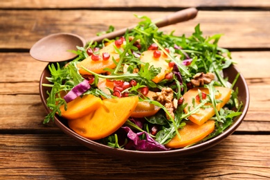 Delicious persimmon salad served on wooden table, closeup