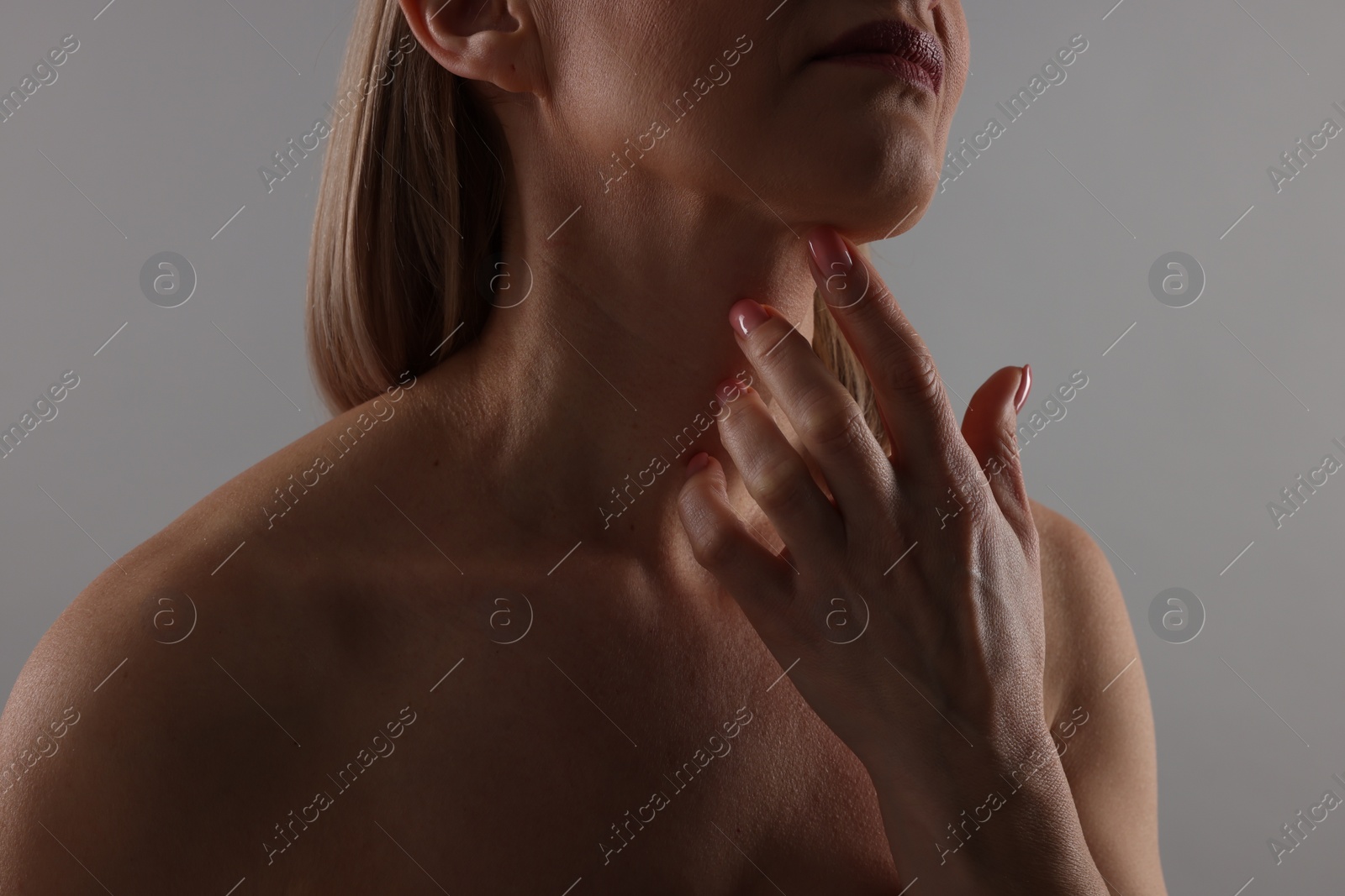 Photo of Woman touching her neck on grey background, closeup