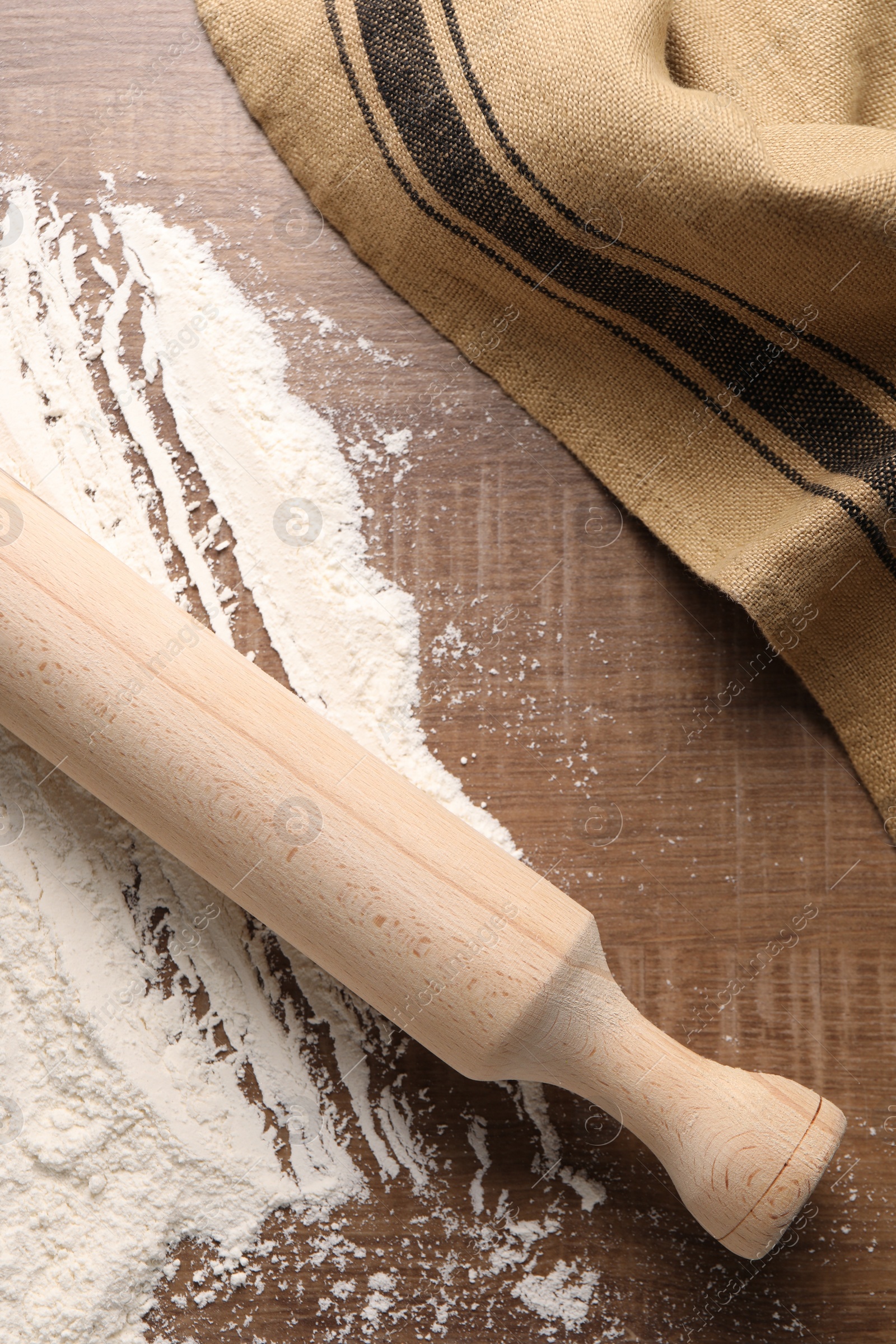 Photo of Scattered flour and rolling pin on wooden table, top view