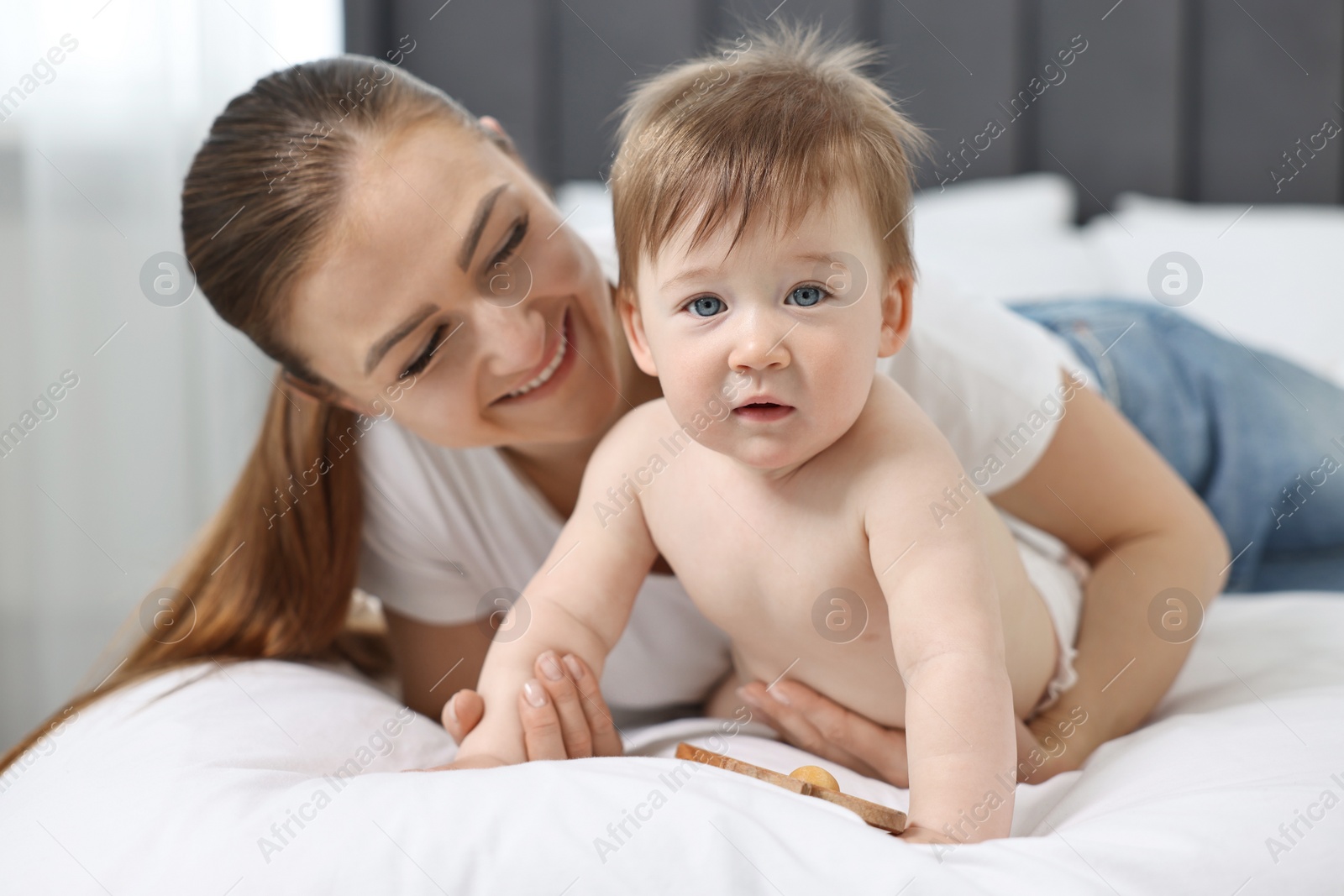 Photo of Happy mother with her baby on bed at home