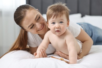 Happy mother with her baby on bed at home