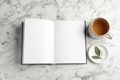 Photo of Flat lay composition with cup of hot green tea and notebook on white marble table. Space for text