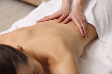 Photo of Woman receiving back massage on couch in spa salon, closeup