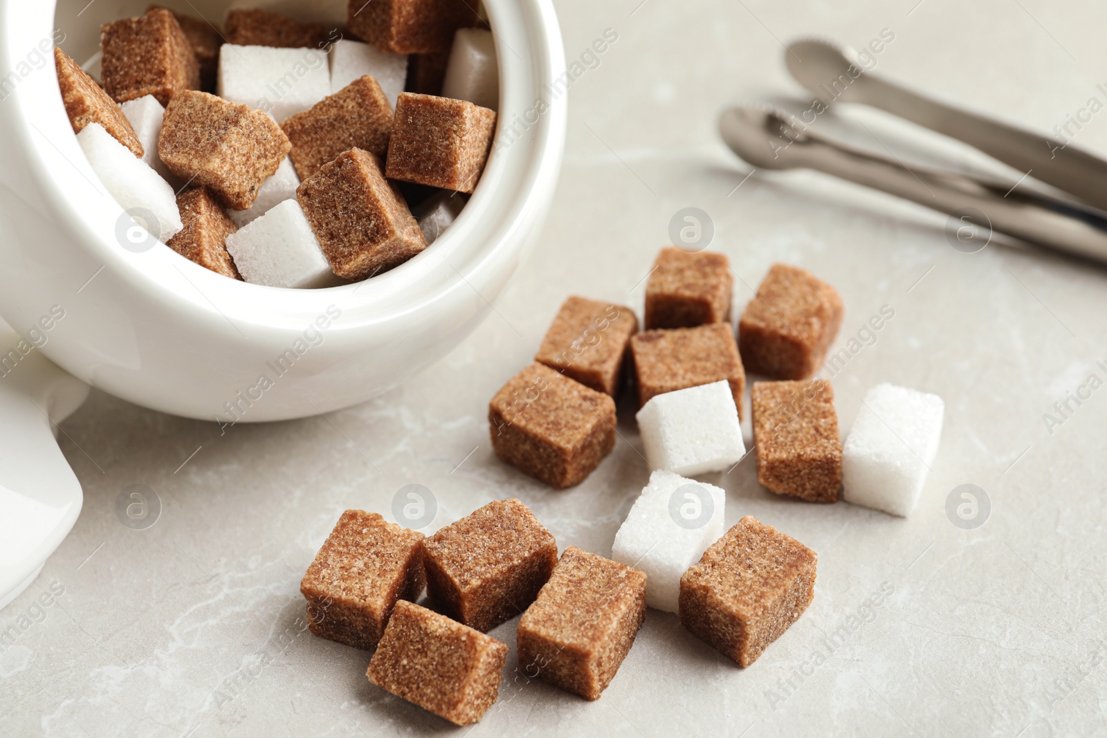 Photo of Bowl and refined sugar cubes on light table, closeup