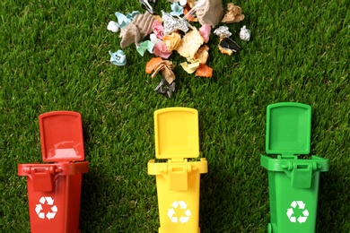 Photo of Trash bins and different garbage on green grass, top view. Waste recycling concept