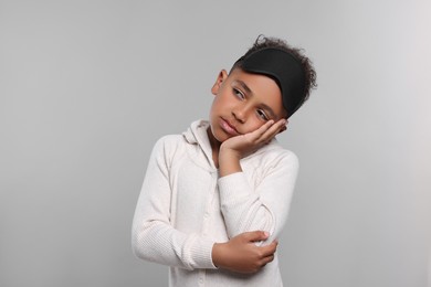 Boy with sleep mask on grey background. Insomnia problem